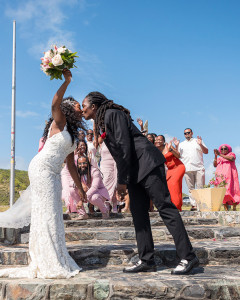 Joyful first kiss as husband and wife on Point Udall, the easternmost point of the United States in St. Croix, with dramatic cliffs and crashing waves below.
