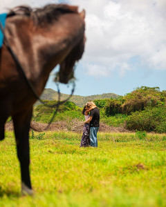 Beautiful couple kissing with their horse watching on the farm in St Croix