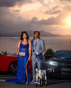 Elegant prom couple posing with a goat in formal attire during golden hour