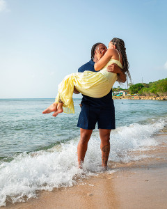 Man carrying his new fiancee to celebrate at the beach