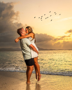 Couple embracing on the beach during a vibrant sunset during their engagement photoshoot