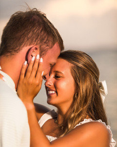 Engaged couple laughing together during a beach sunset portrait session.