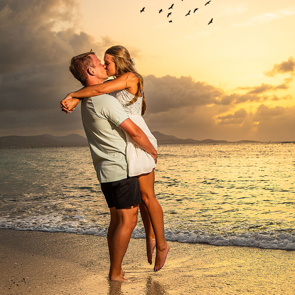 Couple embracing on the beach during a vibrant sunset during their engagement photoshoot