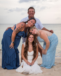 Parents and children posing along the shoreline during a tropical sunset family photoshoot.